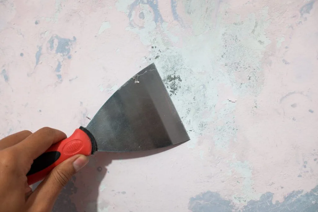 Wall paint scraper being held against